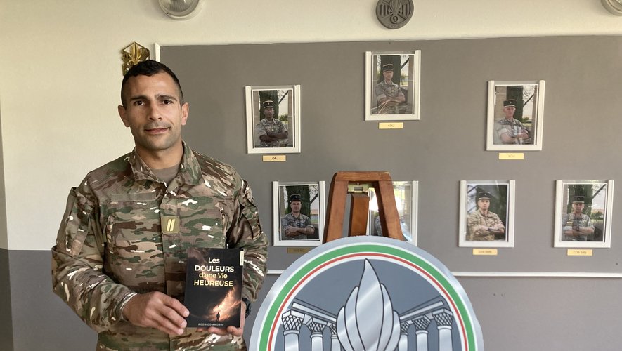 Le sergent Rodrigo Amorim au 1er REG, tenant son livre Les Douleurs d'une Vie Heureuse devant les portraits du régiment